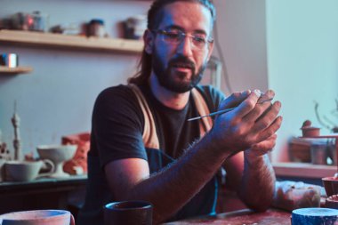 Çömlek atölyesinde gözlüklü çalışkan dalgın adam yeni proje için workig olduğunu.