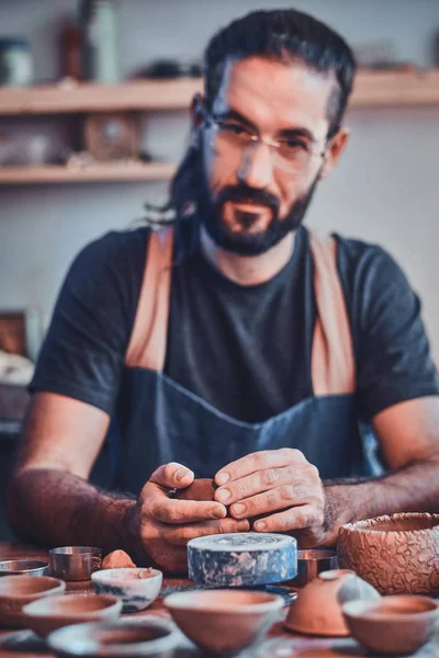 Diligent pensive man in glasses at his  pottery workshop is workig for new project. — Stock Photo, Image