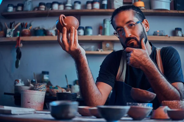 Sceptical  man is looking at his own work, ceramic teapot. — Stock Photo, Image