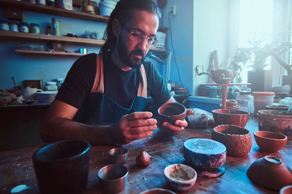 Pensive Potter i glas på sin egen verkstad är workig på en ny handgjorda tekanna. — Stockfoto