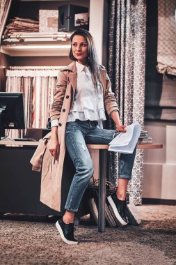 Neşeli tasarımcı atölyesinde masada oturuyor.