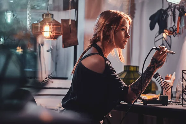 Привлекательная женщина занимается пайкой в собственной мастерской по изготовлению ламп. . — стоковое фото