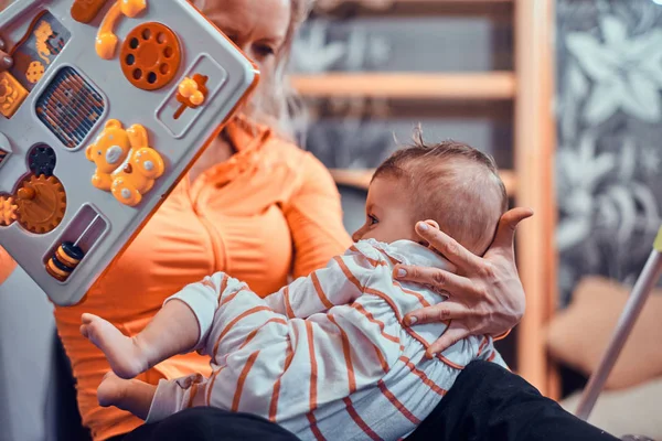 Vrolijke moeder speelt met haar pasgeboren baby tijdens het wachten op een arts — Stockfoto