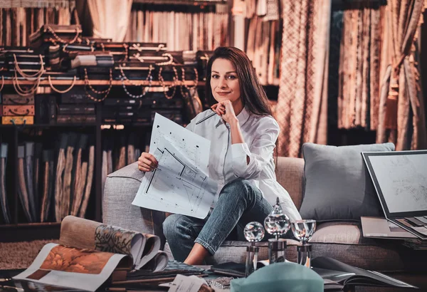 Hermosa mujer está sentada en el sofá en su estudio curtians —  Fotos de Stock