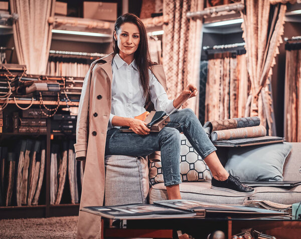 Fashionable talented designer is sitting on the sofa at her own textile workshop