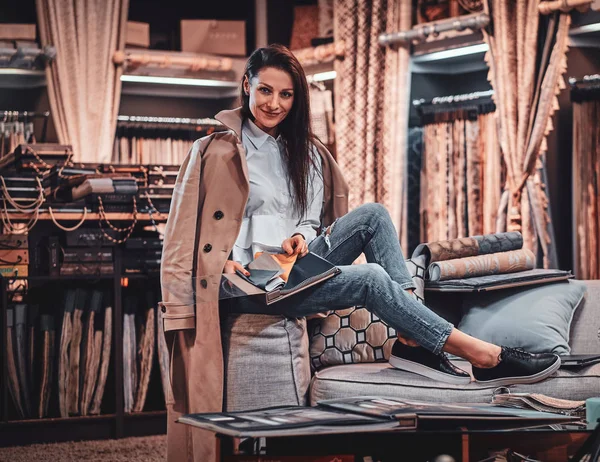 Elegante designer talentoso está sentado no sofá em sua própria oficina têxtil — Fotografia de Stock