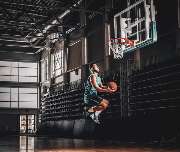 Black basketball player in action in a basketball court.