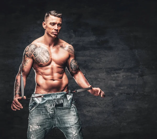 A man with a tattoo on his chest dressed in a jeans. — Stock Photo, Image