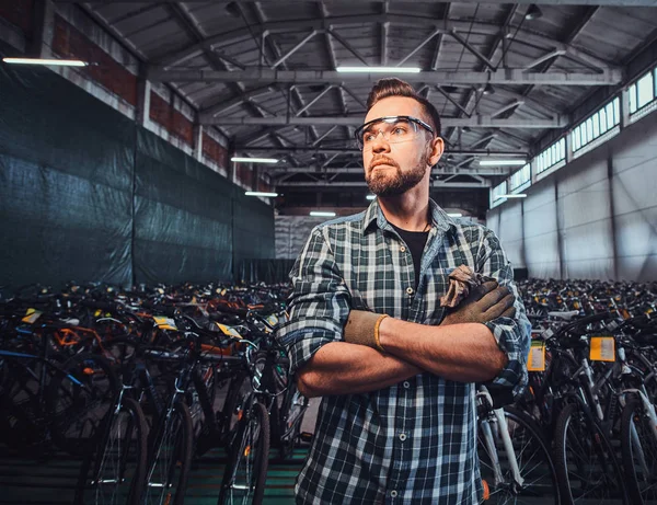 Pensive man crossed his hads is posing at his own warehouse.