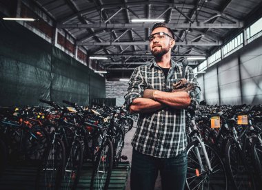 Genç ve çekici bir adam fotoğrafçı için bisiklet depolarında poz veriyor..