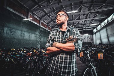 Genç ve çekici bir adam fotoğrafçı için bisiklet depolarında poz veriyor..