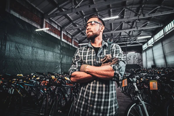 Jovem atraente homem está posando em armazéns de bicicletas para fotógrafo . — Fotografia de Stock