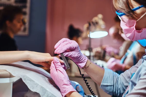 Una mujer está recibiendo cuidado de uñas de la manicura . —  Fotos de Stock