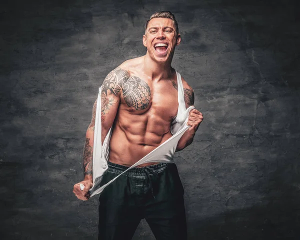 Спортивный мужчина с татуировкой разорвал футболку на груди . — стоковое фото