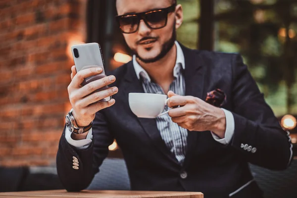 Serious hombre exitoso está llamando por móvil y disfrutando de su café . —  Fotos de Stock