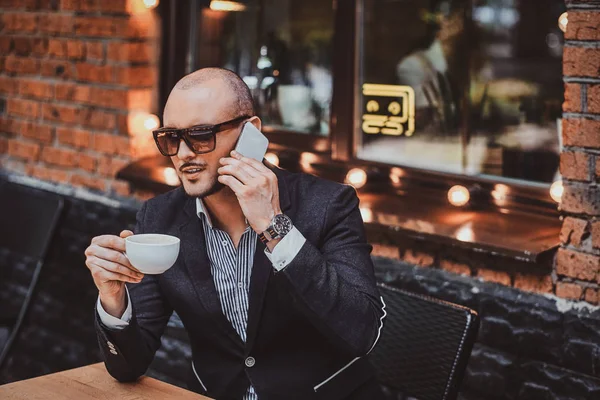 Serious hombre exitoso está llamando por móvil y disfrutando de su café . — Foto de Stock