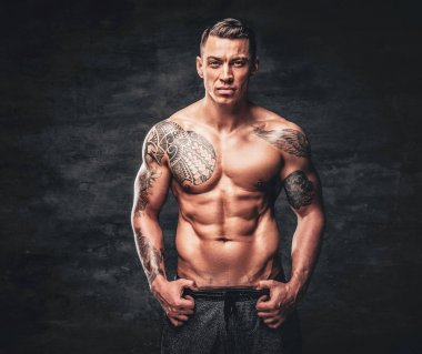 Gri arka plan üzerinde göğsünde dövme olan bir adam.