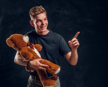 Mutlu gülümseyen adam peluş ayısına bir şeyler gösteriyor.