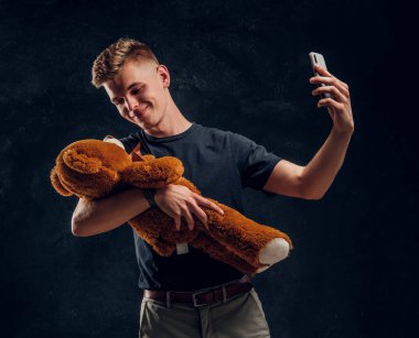 Young attractive man is making selfie with plush toy
