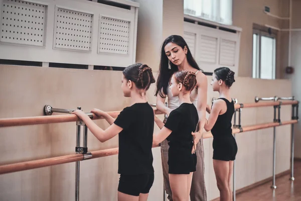 재능있는 트레이너는 발레 운동을하는 방법을 어린 소녀에게 보여주고 있습니다. — 스톡 사진