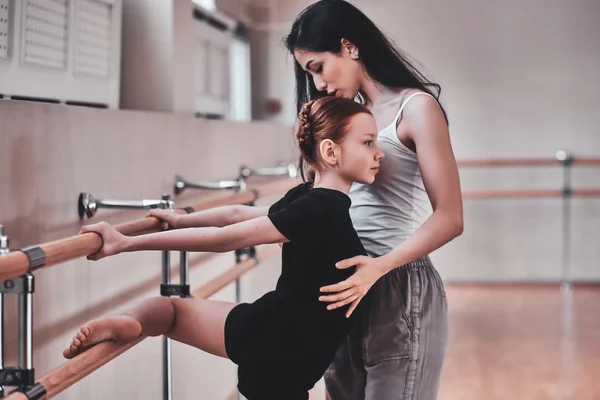 Молодая задумчивая девушка проходит специальную балетную подготовку у прилежного тренера — стоковое фото
