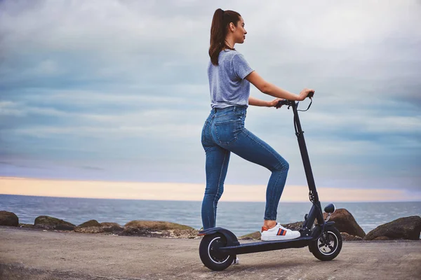 Sportowa kobieta jeździ Electro Scooter przez wybrzeże — Zdjęcie stockowe