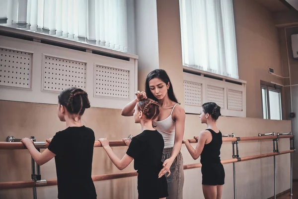 재능있는 트레이너는 발레 운동을하는 방법을 어린 소녀에게 보여주고 있습니다. — 스톡 사진