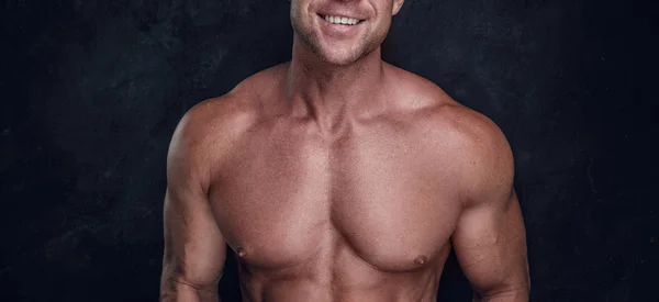 Hombre con hermoso cuerpo muscular está posando sobre fondo oscuro —  Fotos de Stock