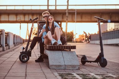 Scooter'ları ile gün batımının tadını çıkaran çekici çift