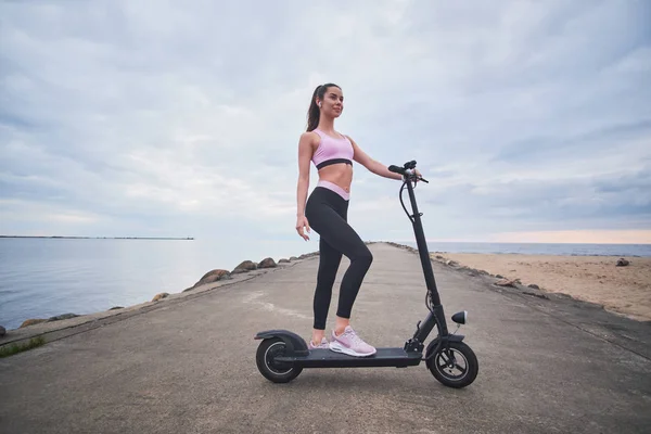 Mooie vrouw rijdt haar scooter door de kust — Stockfoto