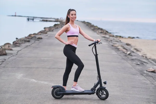 Mujer bonita está conduciendo su scooter a orillas del mar — Foto de Stock