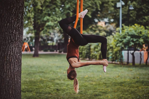 Young attractive girl with long hair is doing exercises on sling in the park. — 스톡 사진
