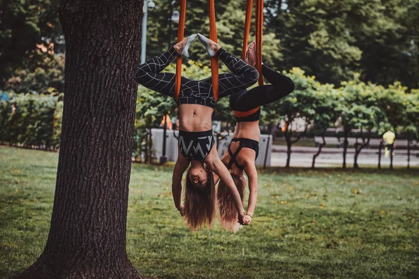 Twee gelukkige vrolijke meiden doen oefeningen ondersteboven — Stockfoto