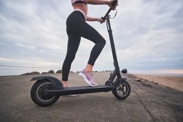 Sportowa kobieta jeździ Electro Scooter przez wybrzeże — Zdjęcie stockowe