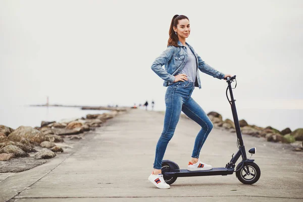 Deportiva mujer está montando electro scooter por la playa — Foto de Stock