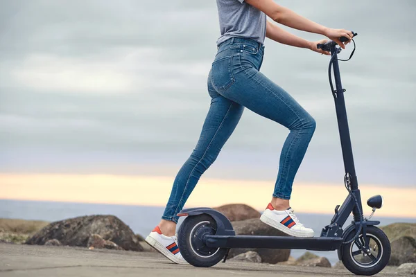 Deportiva mujer está montando electro scooter por la playa —  Fotos de Stock
