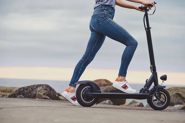 Sporty woman is riding electro scooter by seaside — Stock Photo, Image