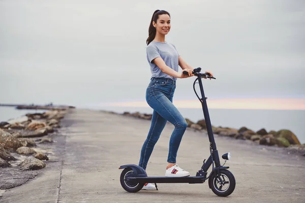 Спортивна жінка їде електро скутер на узбережжі — стокове фото