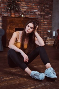 Uzun saçlı güzel kız yerde oturuyor.