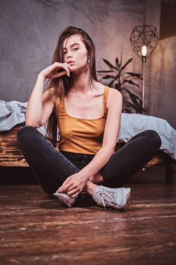 Young woman in sheakers is sitting on the floor