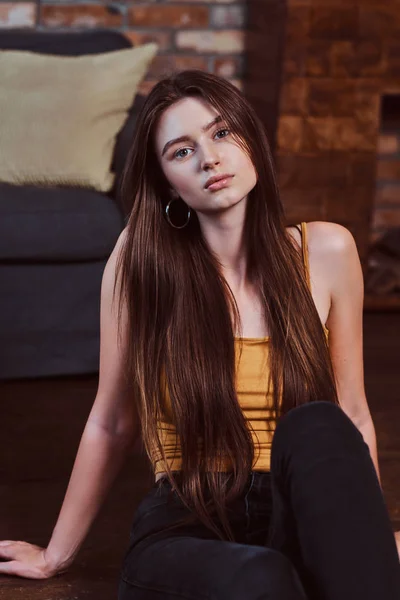 Hermosa chica con el pelo largo está sentado en el suelo . — Foto de Stock