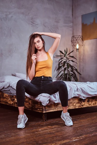 Attraente giovane donna è seduta sul suo letto — Foto Stock