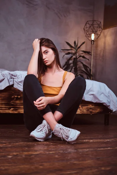 Mladá žena v Sheakers sedí na podlaze — Stock fotografie
