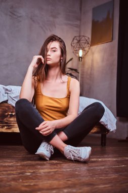 Young woman in sheakers is sitting on the floor