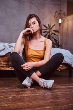 Young woman in sheakers is sitting on the floor