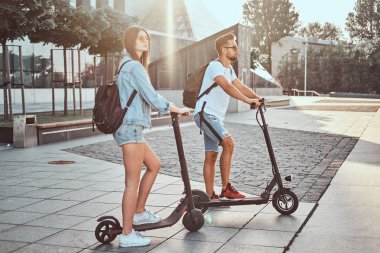 Genç çift, elektro scooterların keyfini çıkarıyor.