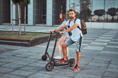 Genç çift, elektro scooterların keyfini çıkarıyor.