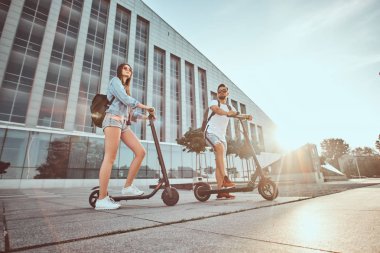 İki arkadaş elektro scooter ile yaz günü tadını çıkarıyor