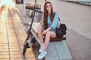 Güzel kız onu scooter ile bankta oturuyor