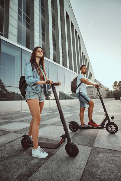 A fiatal pár élvezi az elektro robogókat. — Stock Fotó